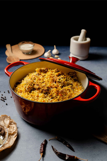 Elvira 5.4L enamel coated cast iron pot filled with Biryani on a dark surface with spices and a mortar and pestle.