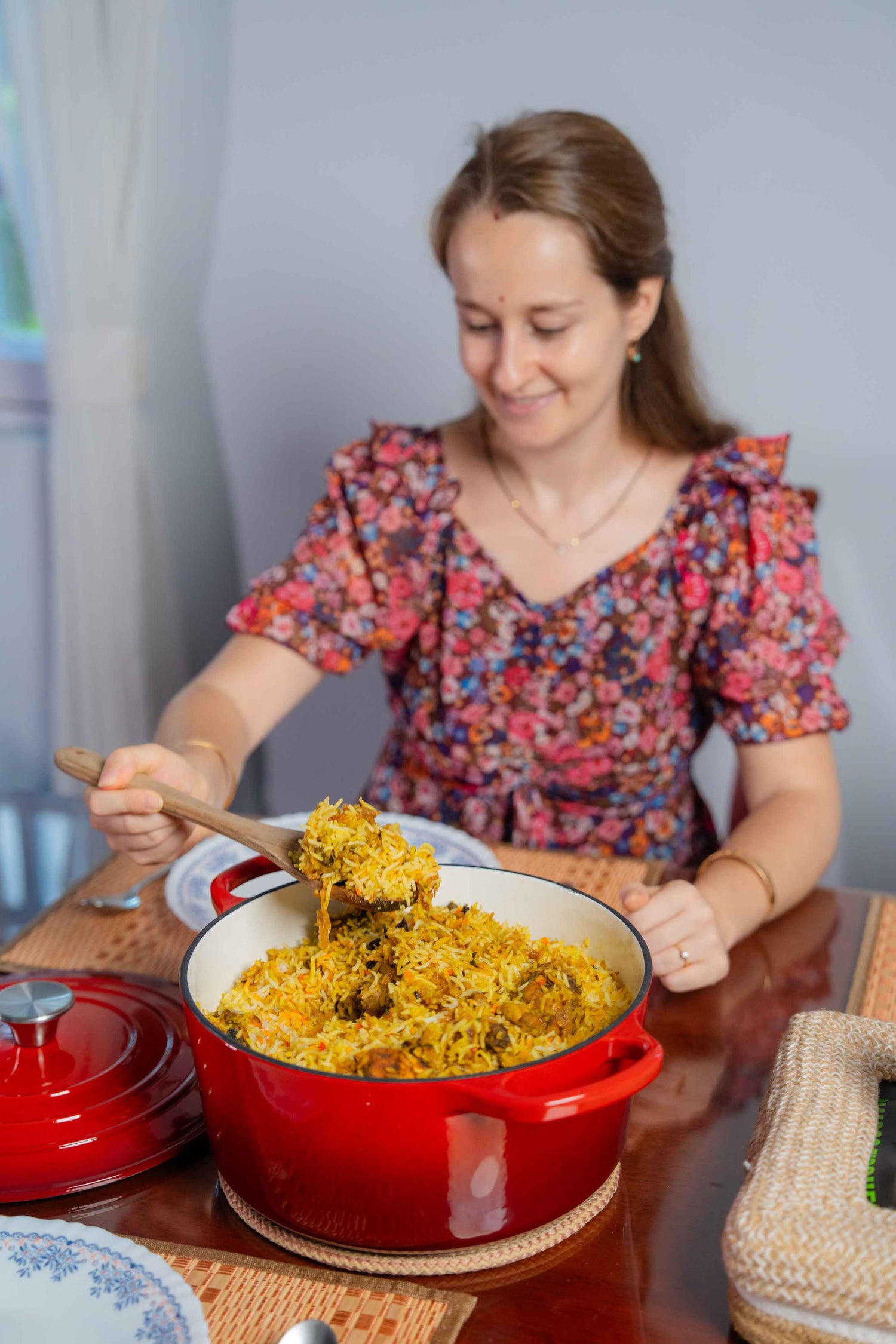 A person serving biryani from an Elvira 4L Enamel Coated Cast Iron Pot